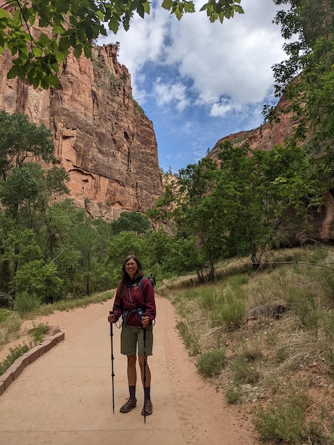 Hikers on a trail in Zion National Park, surrounded by towering sandstone cliffs and lush greenery.