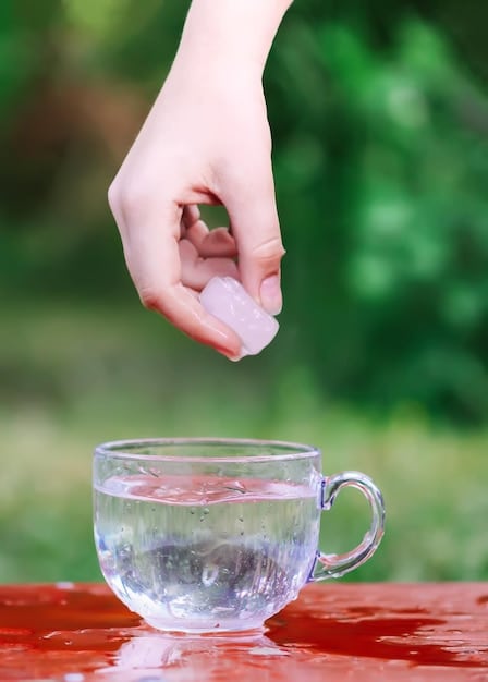 A close-up image of a hand gently touching the clear, mineral-rich water of a hot spring, with sunlight reflecting off the surface. The photo emphasizes the purity and inviting nature of the thermal water.