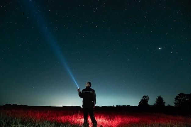 A detailed close-up shot of a red light flashlight illuminating a stargazing map in the hand of a person standing in a dark sky park, with a faint glow highlighting the map's constellations.
