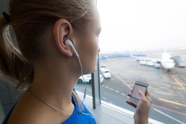 A close-up shot of noise-canceling headphones being worn on a plane, with a blurred background of the airplane cabin.