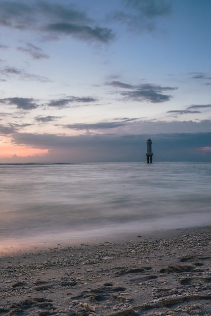 A tranquil beach scene during the off-season, showing a nearly empty beach with calm waters and soft lighting. A few distant figures are visible, enjoying the peacefulness.