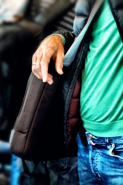 A close-up shot of a traveler's hand reaching into the hidden, zippered pocket inside an anti-theft travel backpack. The pocket is discreet and not easily accessible from the outside.
