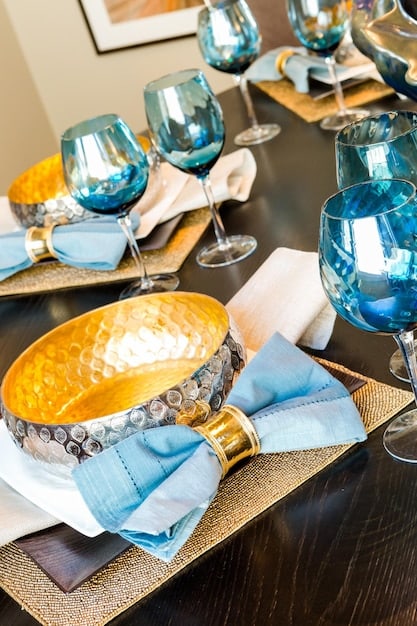 A close-up of a table setting at an all-inclusive resort. The table is elegantly decorated with fine china, silverware, and crystal glassware. A waiter is pouring wine into a glass. The food is gourmet and beautifully presented. This image reflects the high-end dining experience that can be enjoyed with All-Inclusive Resort Deals: Get the Best Value for Your Money.