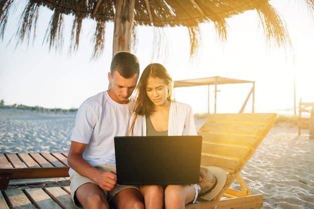 A couple happily using their laptop to book accommodations for their summer vacation. The setting is a cozy kitchen, and the laptop screen displays a travel booking website with various Early Bird Travel Deals: Save Up to 25% by Booking in Advance.