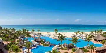 Luxury all-inclusive resort with white sand beach and clear blue ocean, showcasing serene vacation experience.